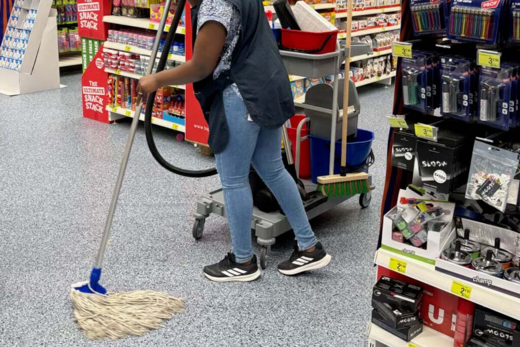 Agent de nettoyage lavant le sol d'un supermarché ou commerce